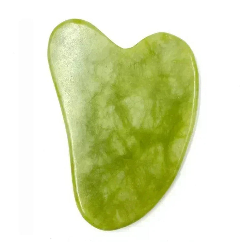 Green jade gua sha tool on a white background
